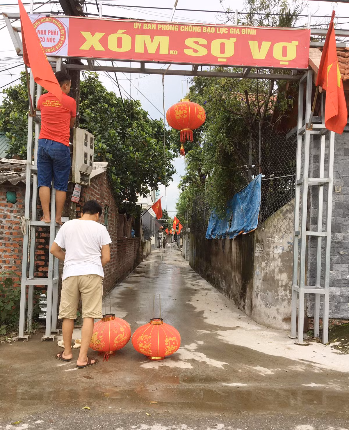 Chiếc biển này được thành viên trong xóm nghĩ ra và cùng các anh em khác treo ở cổng chào để tạo không khí vui vẻ nhân 1 dịp lễ. Chữ "không" trong cả cụm "Xóm không sợ vợ" cũng được viết nhỏ hơn hẳn, nếu không để ý sẽ đọc thành "Xóm sợ vợ". Ảnh: Tổng hợp
