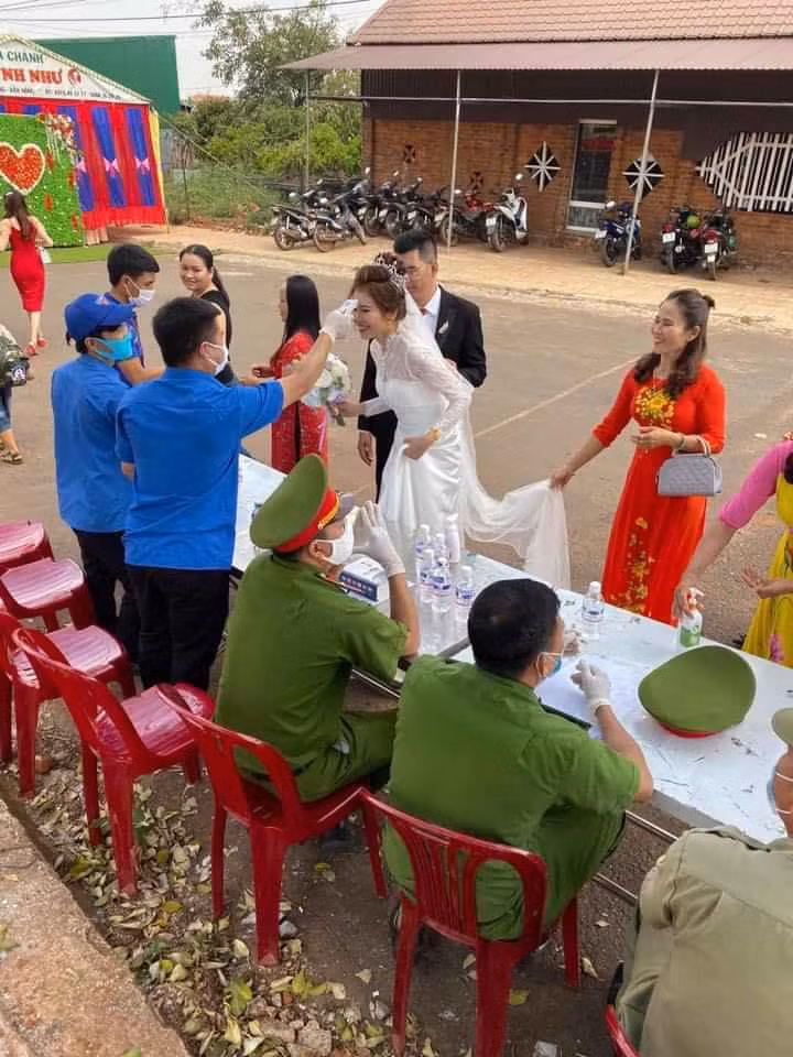 Cô dâu, chú rể và khách mời ai cũng hào hứng, tuân thủ quy trình kiểm tra của các cán bộ công an để phòng tránh dịch Covid-19.