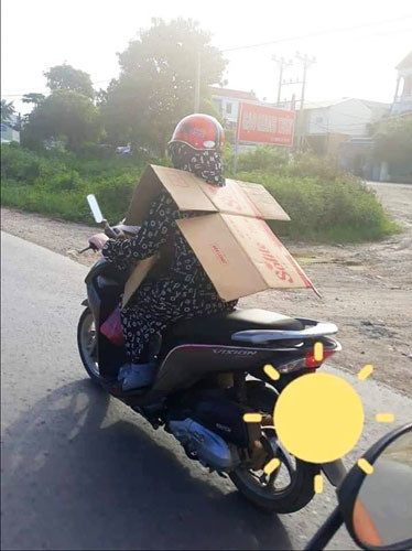 Một "Ninja", theo cách gọi của cư dân mạng dành cho phụ nữ, sử dụng bìa carton để che chắn trước sau dù đã mang đầy đủ đồ chống nắng.
