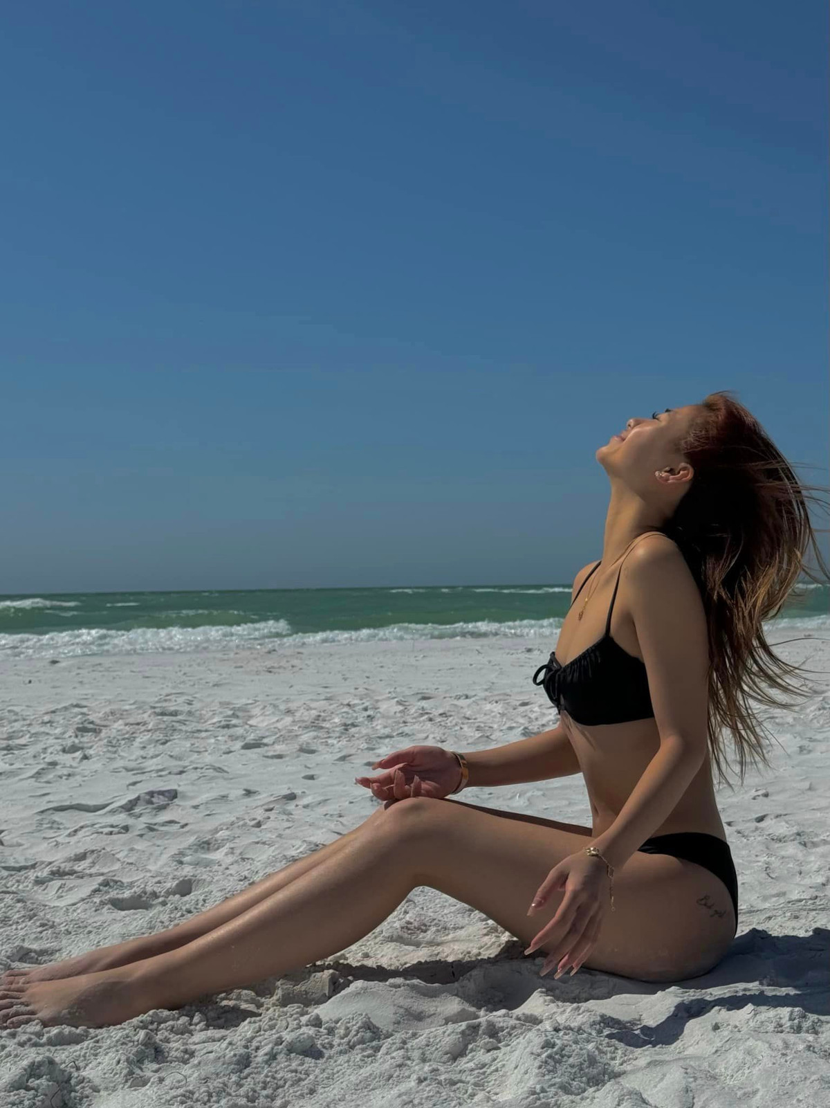 Như Phương diện bộ bikini 2 mảnh màu đen, thả dáng trên bờ biển tắm nắng.