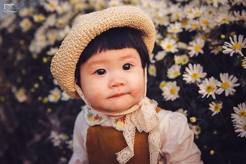 Trong bộ ảnh, Mít có nhiều biểu cảm rất đáng yêu như bặm môi, cười tít mắt, thích thú nghịch hoa cúc họa mi.