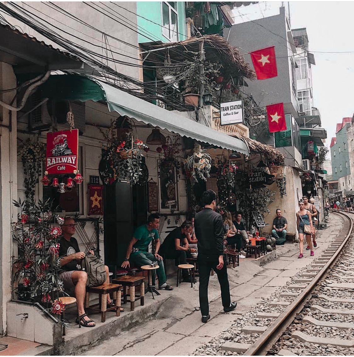 Trước khi tàu chạy khoảng 5 phút, nhân viên quán sẽ đi nhắc nhở và bê bàn ngoài đường sắt vào trong nhà. - Ảnh: _dinhphuongthao_.