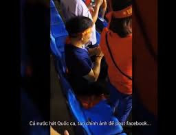 Thậm chí, trong khi mọi người đang đứng dậy để hát Quốc ca thì thanh niên thiếu ý thức này vẫn cứ ung dung ngồi trên lá cờ Tổ quốc và thoải mái chụp hình, chỉnh ảnh. Mặc kệ ánh nhìn không mấy thiện cảm từ những người xung quanh.