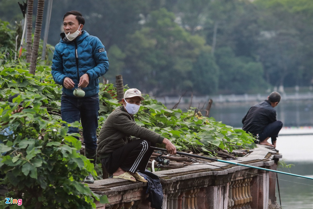 Dù rào chắn đã được lập nên ở công viên Thủ Lệ để ngăn người dân vào trong nhưng nhóm người vẫn trèo lên thành hồ để câu cá.
