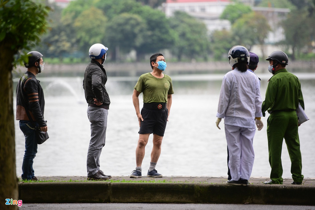 Một người đàn ông tập thể dục phía bên trong công viên Thống Nhất (đứng giữa) đang phân trần với lực lượng trật tự phường Lê Đại Hành. Sau khi nhắc nhở, người này tự giác đi ra ngoài.