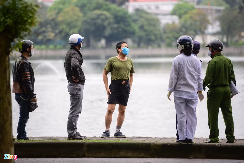 Một người đàn ông tập thể dục phía bên trong công viên Thống Nhất (đứng giữa) đang phân trần với lực lượng trật tự phường Lê Đại Hành. Sau khi nhắc nhở, người này tự giác đi ra ngoài.