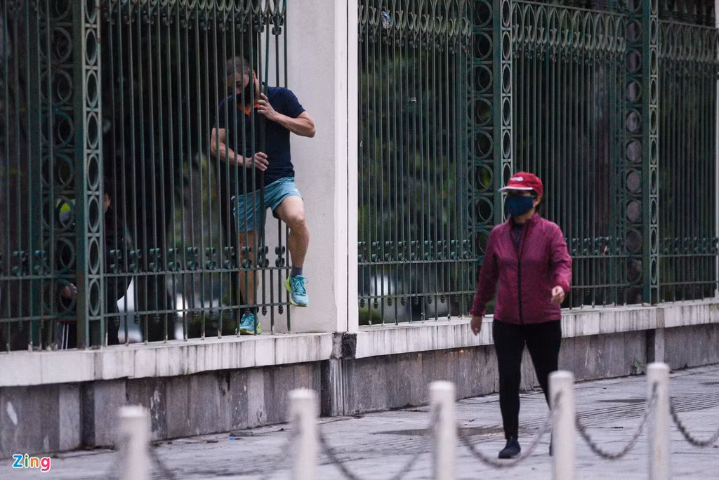 Một số tìm cách vào phía trong công viên để tập thể dục. Tại tường rào mặt phố Nguyễn Đình Chiểu có một vài kẽ hở, dù lách qua rất khó khăn nhưng người đàn ông này vẫn cố gắng trèo qua.