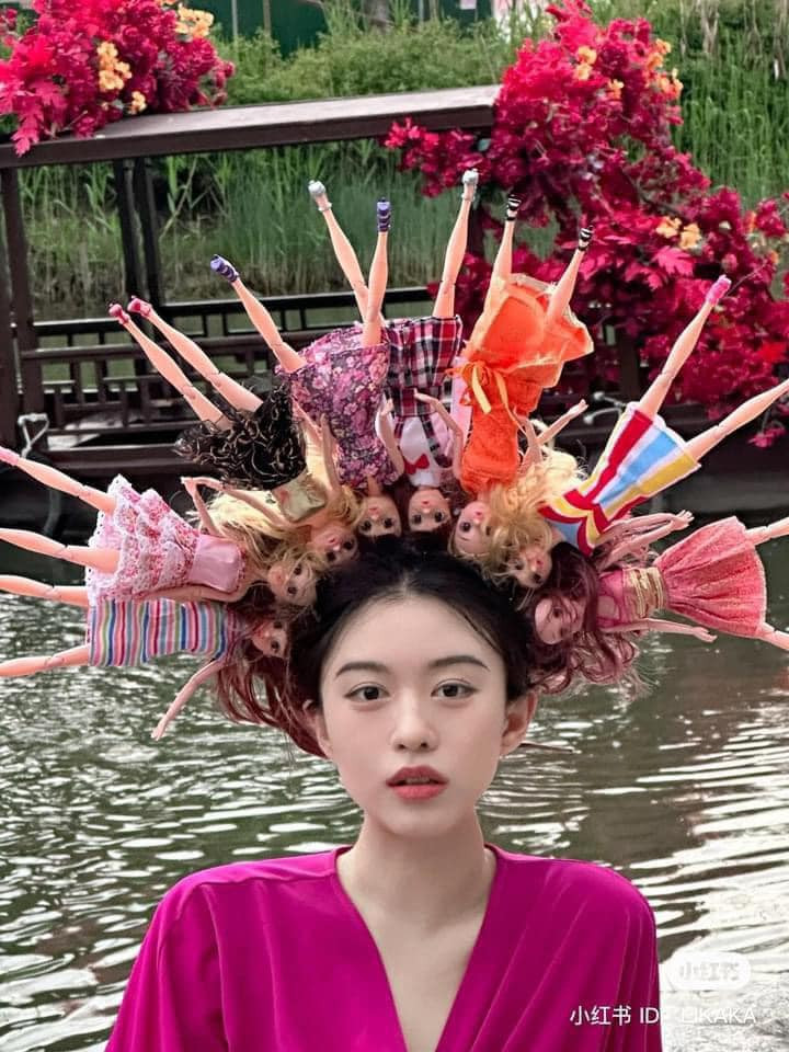 Một cô gái ở Trung Quốc cũng đã theo trend này, thế nhưng thay vì cài hoa, cô nàng cài toàn...búp bê.