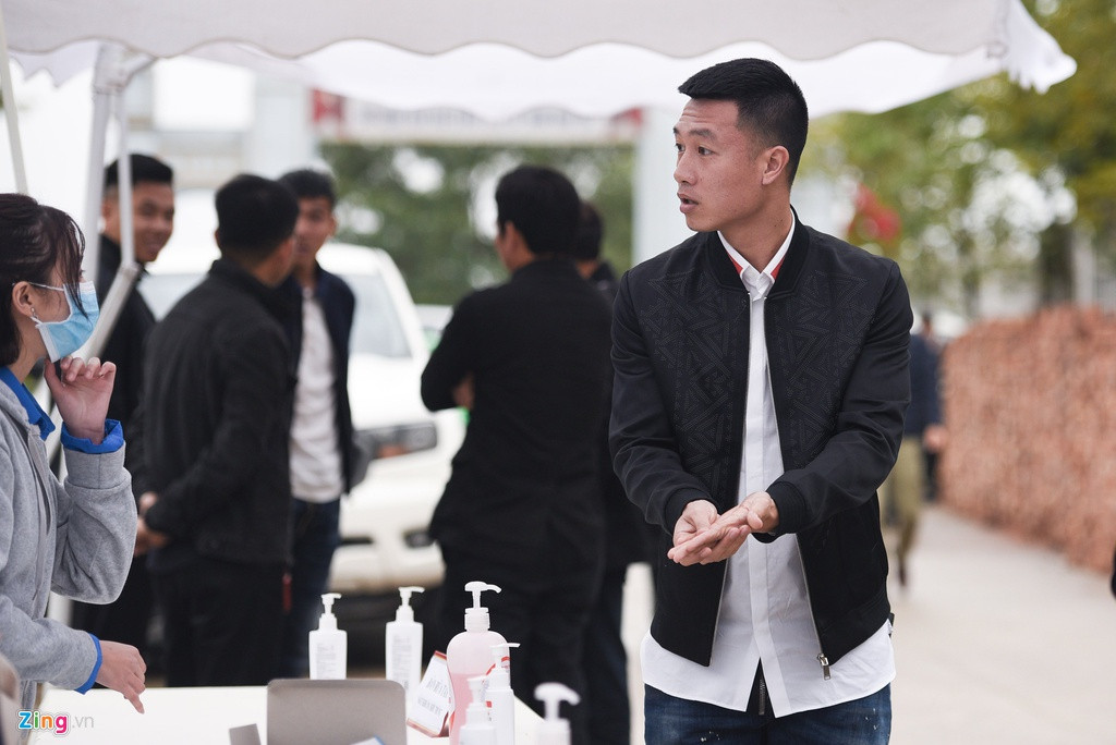 Không chỉ có khẩu trang, ngay bên ngoài cửa trước khi bước vào sân tổ chức đám cưới, rất nhiều các lọ dung dịch rửa tay khô được đặt sẵn để khách mời sát khuẩn, giữ vệ sinh trước khi vào đám cưới. Huy Hùng rửa tay cực kỹ trước khi tham dự đám cưới đồng đội. Ảnh: Zing.