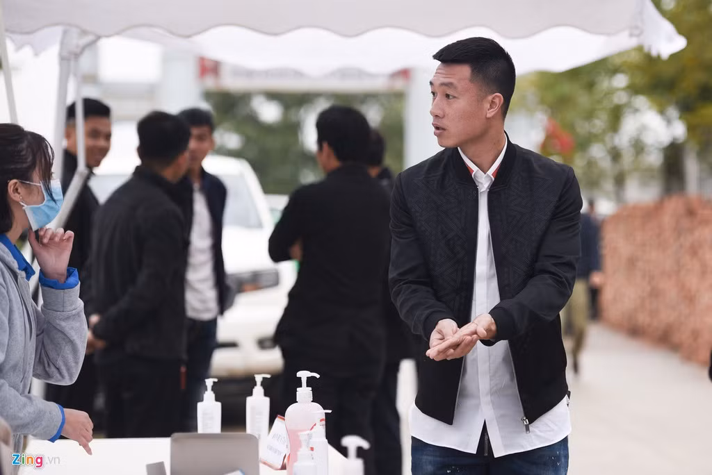 Không chỉ có khẩu trang, ngay bên ngoài cửa trước khi bước vào sân tổ chức đám cưới, rất nhiều các lọ dung dịch rửa tay khô được đặt sẵn để khách mời sát khuẩn, giữ vệ sinh trước khi vào đám cưới. Huy Hùng rửa tay cực kỹ trước khi tham dự đám cưới đồng đội. Ảnh: Zing.