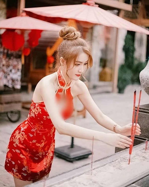 Nàng hot girl diện một chiếc sườn xám Trung Quốc cách tân màu đỏ ngắn cũn cỡn, chủ qua mông một chút, phần ngực khoét sâu để lộ gò hồng đào cùng phần lưng trần vô cùng quyến rũ. Đây sẽ là trang phục cực đẹp nếu như để đi du xuân, dạo phố thế nhưng ở nơi tôn nghiêm như chùa, đền thì lại không hề phù hợp.
