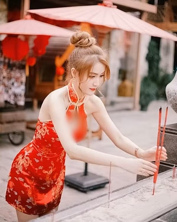 Nàng hot girl diện một chiếc sườn xám Trung Quốc cách tân màu đỏ ngắn cũn cỡn, chủ qua mông một chút, phần ngực khoét sâu để lộ gò hồng đào cùng phần lưng trần vô cùng quyến rũ. Đây sẽ là trang phục cực đẹp nếu như để đi du xuân, dạo phố thế nhưng ở nơi tôn nghiêm như chùa, đền thì lại không hề phù hợp.