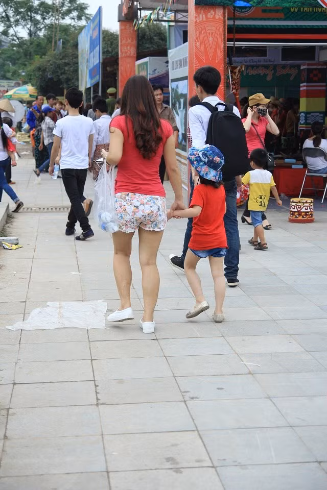 Trong ảnh là người phụ nự mặc quần soóc, đem theo cả trẻ nhỏ tiến về phía lối lên các đền, nơi biển người đang chen lấn nhau.