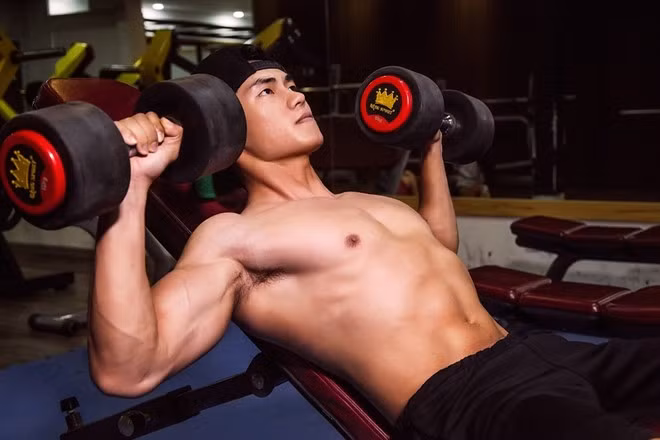 Đẩy tạ đơn trên ghế dốc: Nằm ngửa trên ghế tập tạ dốc, chân đặt trên sàn nhà, nắm tạ với độ rộng vai như hình. Thở ra khi đẩy tạ lên, siết ngực 1 giây, từ từ hít vào khi hạ xuống. Lặp lại động tác đến khi đạt yêu cầu.