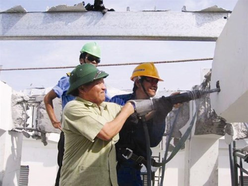 Chủ tịch Nguyễn Quốc Triệu khoan vào thanh dầm chịu lực trước sự chứng kiến của những người công nhân đang tháo dỡ công trình số 9 Đào Duy Anh. Ảnh nguồn: Tiền Phong