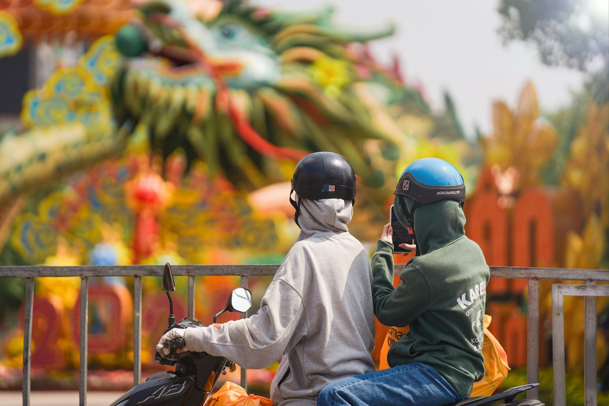 Người dân đi ngang qua đường Nguyễn Huệ, Quận 1 cũng tranh thủ dừng lại chụp ảnh linh vật rồng ngay khu vực cổng chào của đường hoa.