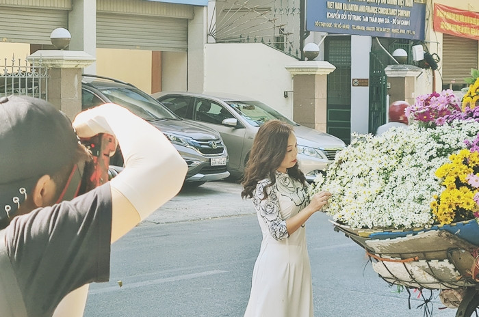 Cô gái xinh xắn tạo dáng chụp ảnh bên xe bán hoa cúc họa mi.