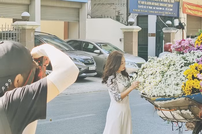 Cô gái xinh xắn tạo dáng chụp ảnh bên xe bán hoa cúc họa mi.