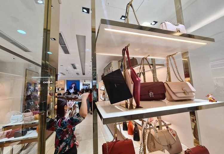 Khách hàng tham khảo kỹ mẫu mã và giá cả của những chiếc túi xách giá tiền triệu đang được giảm giá trước khi rút hầu bao.