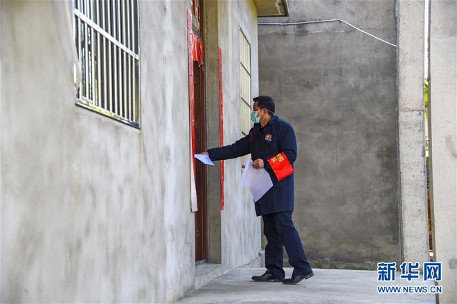 Một tình nguyện viên khác đến từng nhà để phát bản quy định phòng chống dịch bệnh.