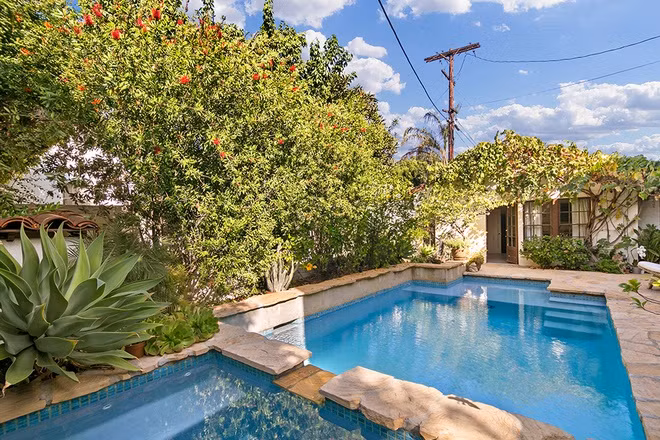 Hồ bơi ngoài trời được thiết kế độc đáo, nằm giữa không gian sân vườn xanh mướt với nhiều loại cây khác nhau.