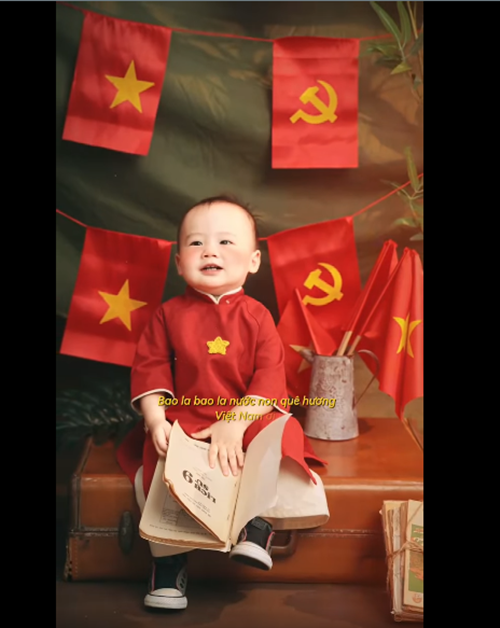 Bé Tino diện áo dài màu đỏ, có hình ngôi sao.