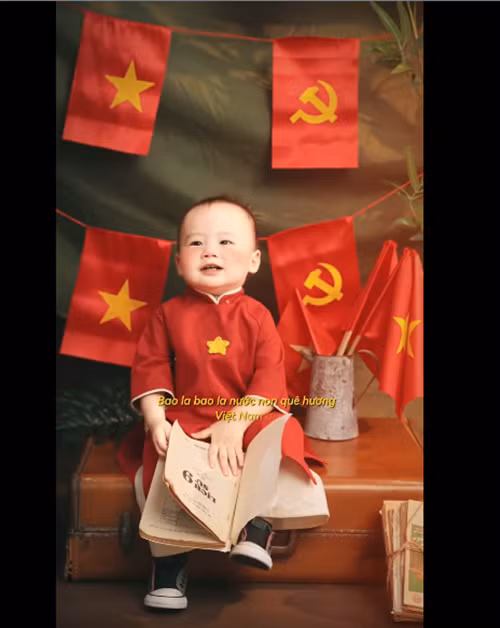 Bé Tino diện áo dài màu đỏ, có hình ngôi sao.