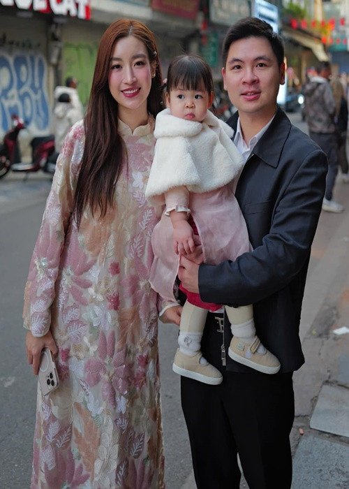 Bé Tuệ An đi giày búp bê, mặc áo dài, áo khoác lông đón Tết cùng bố mẹ.