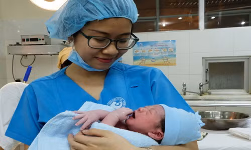 Bác sĩ trẻ Lưu Minh Trâm vui mừng đón một em bé vừa mới chào đời trong ca trực giao thừa đầu tiên - Ảnh: VŨ THỦY