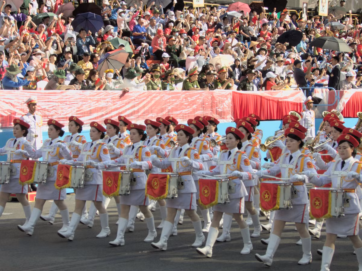 Khối nữ quân nhạc mặc quân phục màu trắng, đội mũ beret đỏ, đeo găng tay trắng và thắt lưng vàng.