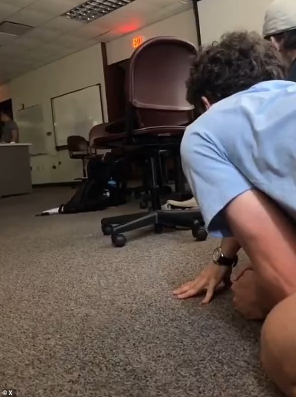 Một sinh viên chia sẻ đoạn video được quay bên trong lớp học cho thấy nhiều người sợ hãi co ro dưới gầm bàn. Ảnh: X.