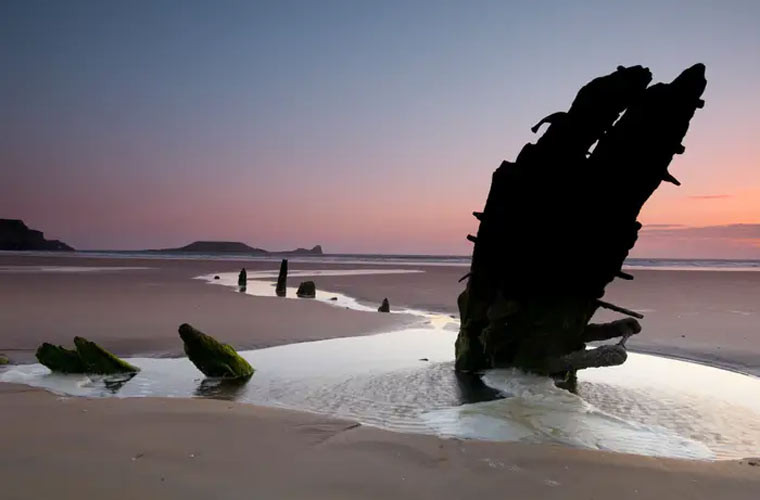 Phần còn lại của con tàu Helvetia, một con tàu của Na Uy từ thế kỷ 19, nằm rải rác trên bãi cát ở vịnh Rhossili, Swansea, xứ Wales.