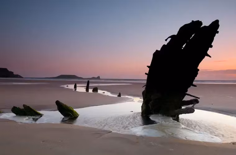 Phần còn lại của con tàu Helvetia, một con tàu của Na Uy từ thế kỷ 19, nằm rải rác trên bãi cát ở vịnh Rhossili, Swansea, xứ Wales.