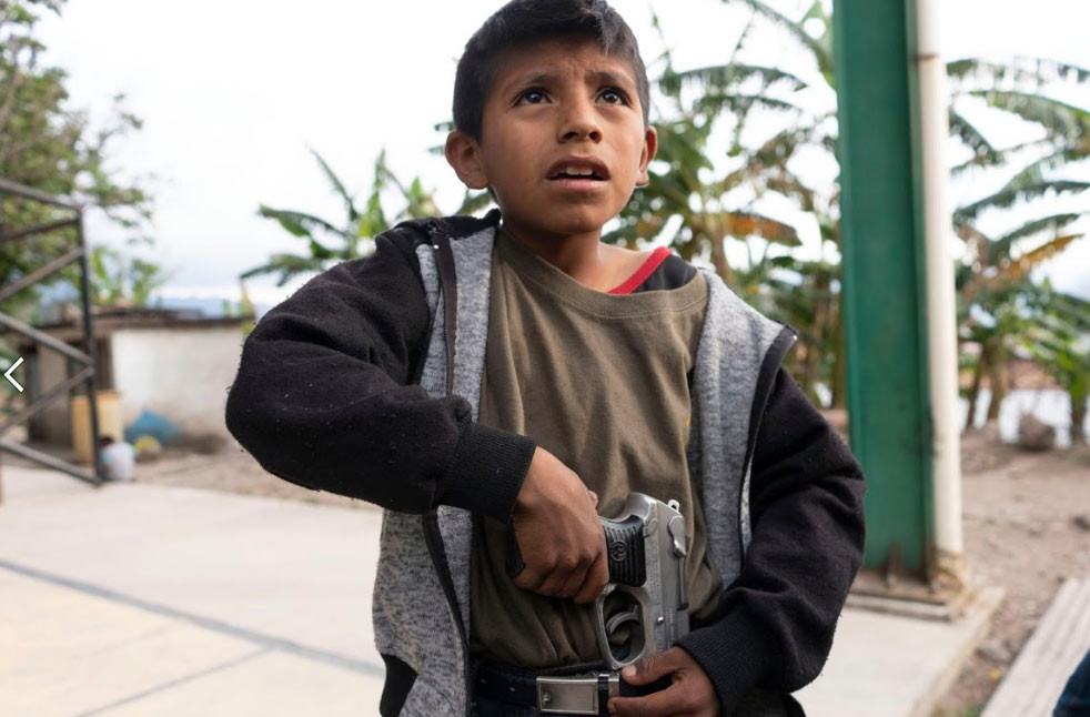 Miguel, 11 tuổi, mang theo khẩu súng của bố và "khoe" với phóng viên kỹ năng dùng súng của mình. Mời độc giả xem thêm video: Biểu tình vụ 43 sinh viên mất tích tiếp diễn tại Mexico (Nguồn video: VTC14)