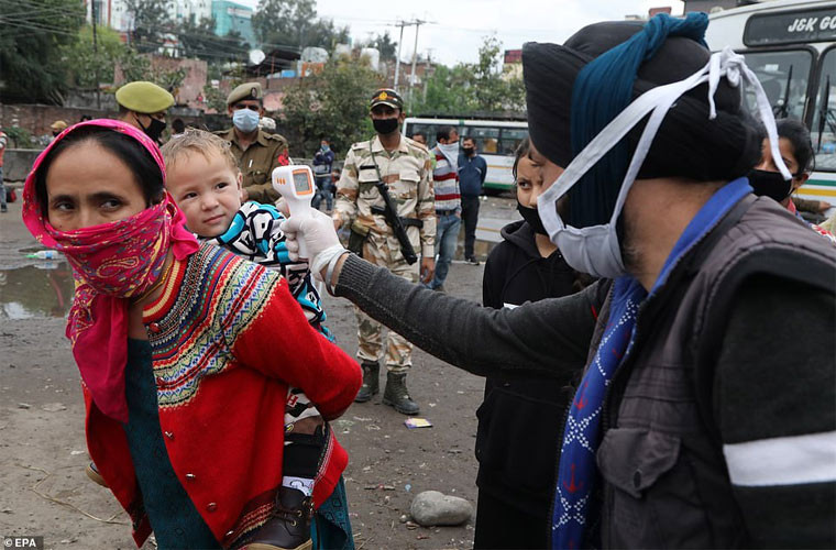 Nhà chức trách đang kiểm tra nhiệt độ của các hành khách chuẩn bị lên xe bus để di chuyển về nhà ở nông thôn.