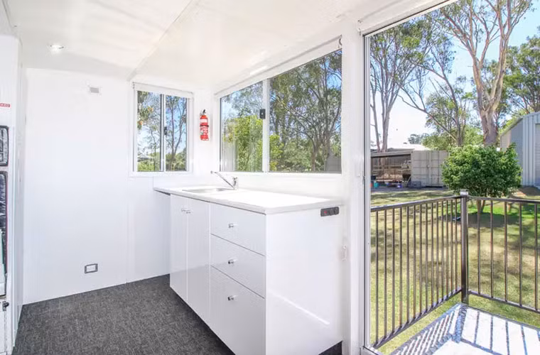 Bếp nhỏ nhưng có đủ bồn rửa, tủ bếp và chỗ kê tủ lạnh mini. Dưới sàn nhà còn có bể nước nóng và bơm nước. Ngôi nhà sử dụng điện từ nguồn năng lượng mặt trời và pin.