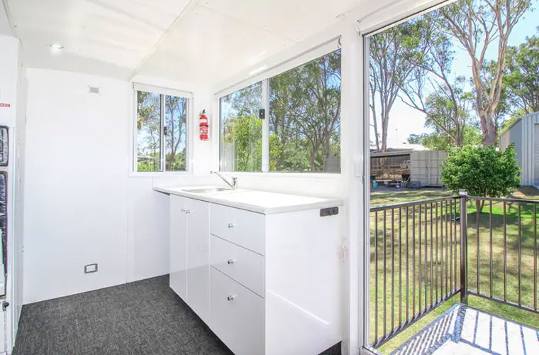 Bếp nhỏ nhưng có đủ bồn rửa, tủ bếp và chỗ kê tủ lạnh mini. Dưới sàn nhà còn có bể nước nóng và bơm nước. Ngôi nhà sử dụng điện từ nguồn năng lượng mặt trời và pin.