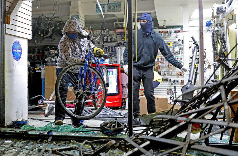 Kẻ cướp đập phá một cửa hàng bán xe đạp rồi lấy xe mang ra khỏi cửa hàng.