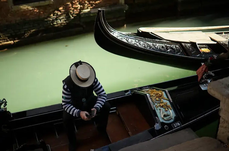 Những người chèo thuyền đang ngồi đợi khách dọc các kênh đào vắng vẻ ở Venice (Italy).