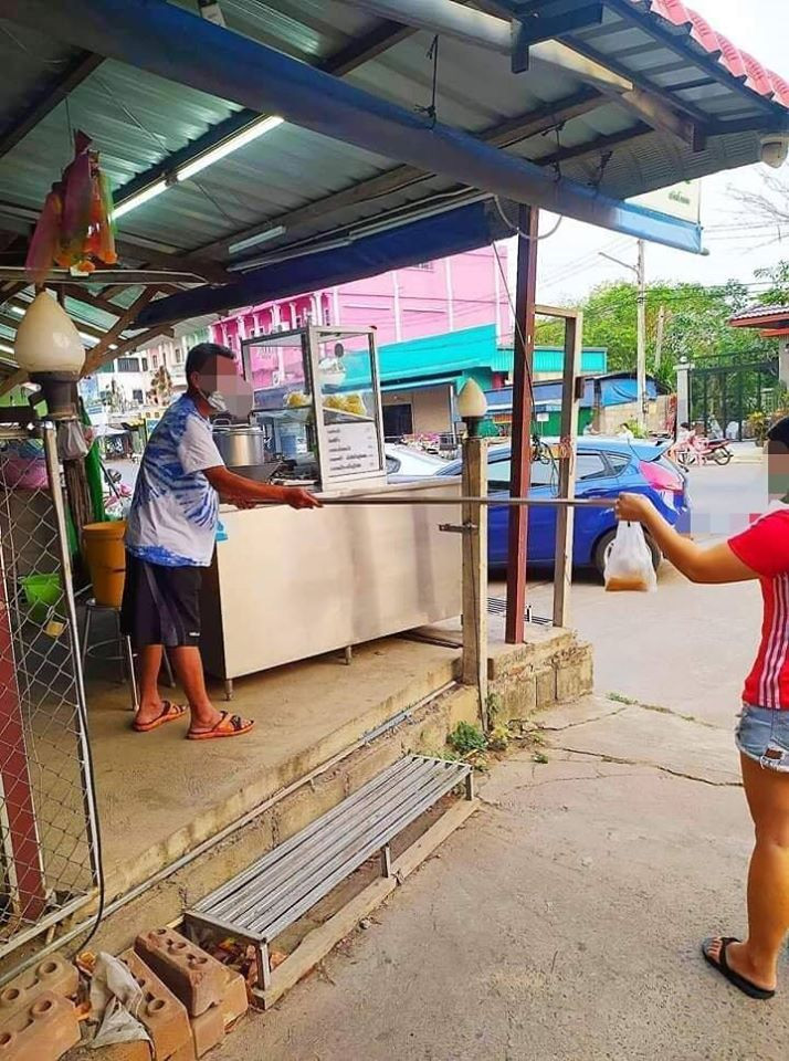 Đưa, nhận đồ bằng một chiếc gậy gỗ giữa người mua và bán là một trong những cách người Thái Lan chọn để tránh tiếp xúc gần, giảm khả năng lây nhiễm Covid-19.