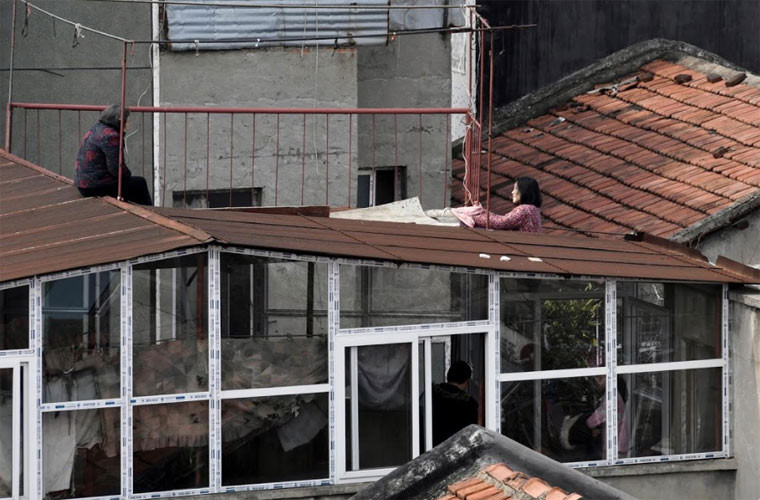 Hai người phụ nữ tranh thủ vừa phơi quần áo, vừa nói chuyện với nhau.