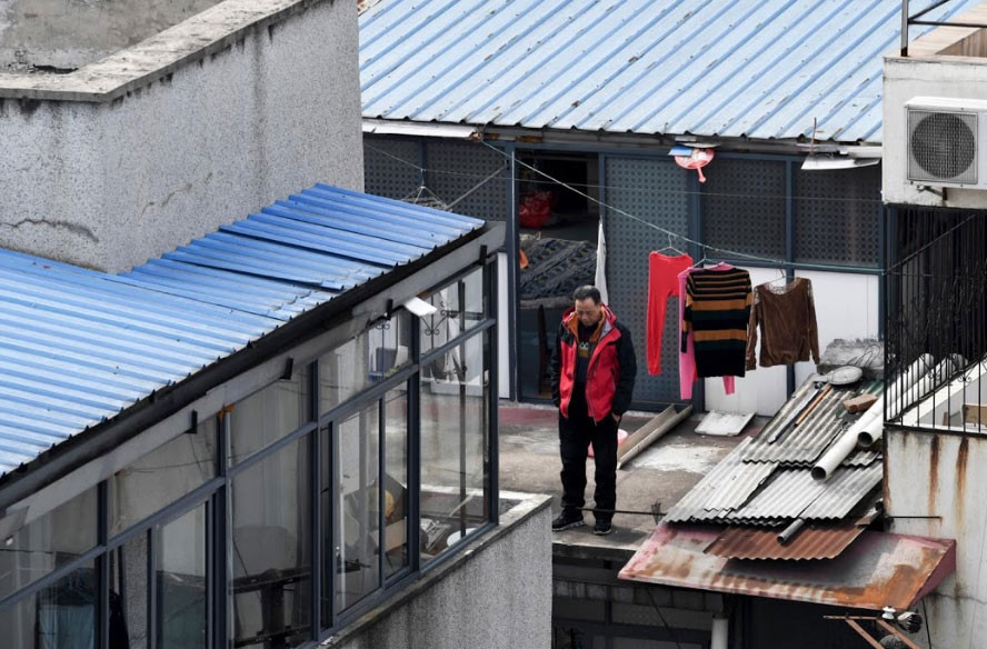 Một người đàn ông khác đang đứng trên tầng thượng, mắt ngóng xuống dưới đường.