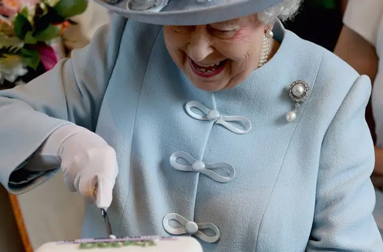 Nữ hoàng tỏ rõ niềm hạnh phúc khi cắt miếng bánh đầu tiên tại sự kiện của Viện Liên đoàn Phụ nữ Quốc gia tổ chức tại Hội trường Hoàng gia Albert.