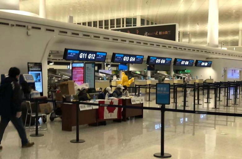 Các nhân viên sân bay đeo khẩu trang khi làm việc ở sân bay Vũ Hán để kiểm tra hành khách Canada sơ tán khỏi Vũ Hán.