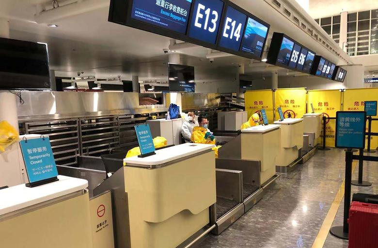 Nhân viên mặc đồ bảo hộ chờ kiểm tra hành khách tới để lên máy bay ở Vũ Hán.