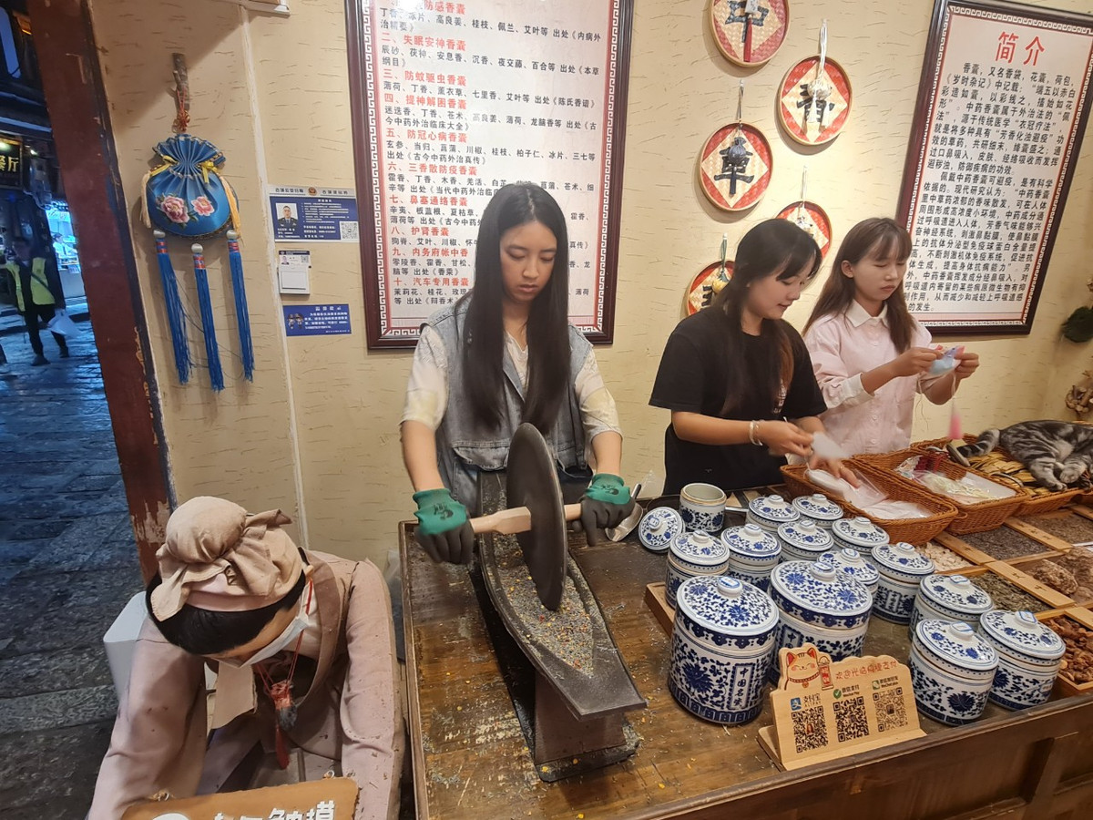 Một cô gái đang nghiền hương liệu để cho vào những chiếc túi thơm, bày bán cho du khách.