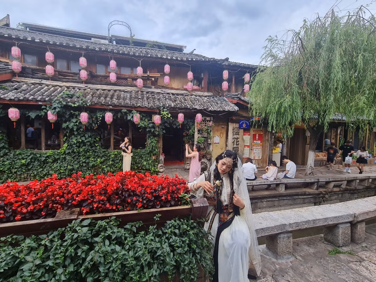 Những thiếu nữ hóa trang trong trang phục cổ khiến cảnh sắc bỗng như quay trở lại cả ngàn năm trước. Những cô gái Nạp Tây mộc mạc, dân dã bỗng hiển hiện ngay trước mắt, ở nơi cổ trấn đẹp tựa chốn thần tiên chỉ nhìn thấy trong phim ảnh.