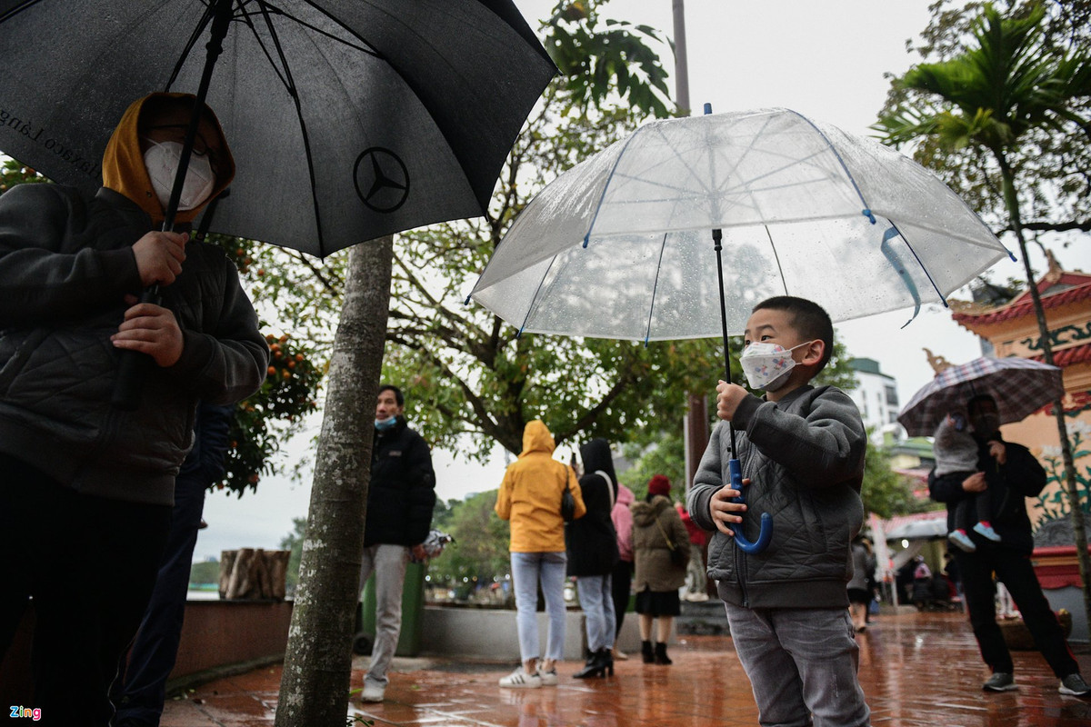Trong chiều 13/2, Hà Nội mưa phùn, nhiệt độ giảm còn 13-14 độ C. Nhiều người phải mang theo ô, mũ khi đi lễ phủ.