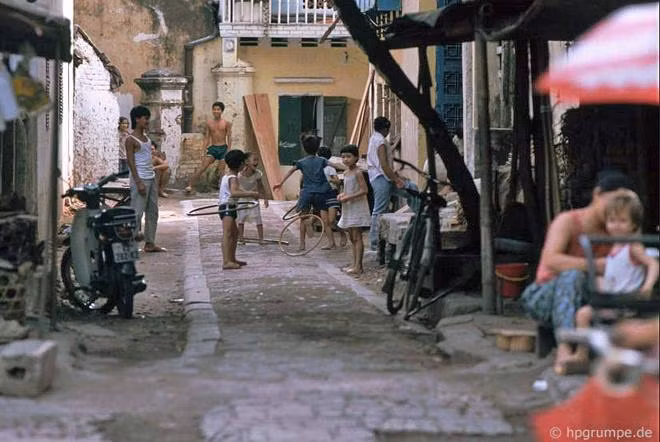 Một số trẻ em chơi lắc vòng trong ngõ nhỏ.