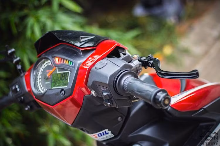 Nằm ở phía trên phần đầu, một tấm ốp cản gió đã được lắp ở phía trên đèn pha của chiếc Exciter 150 độ kiểng. Vốn có cụm đồng hồ điện tử nguyên bản khá hiện đại, tuy nhiên chiếc xe vẫn được chủ nhân thay đồng hồ độ Koso dành riêng cho Exciter 150. Hai bên tay lái là tay côn CRG và cùm phanh Brembo.